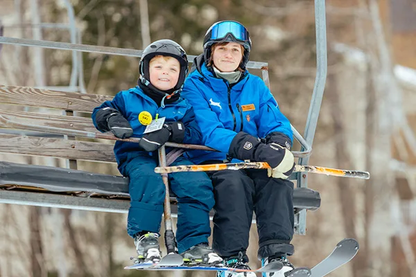 Jiminy instructor with young skier on chairlift