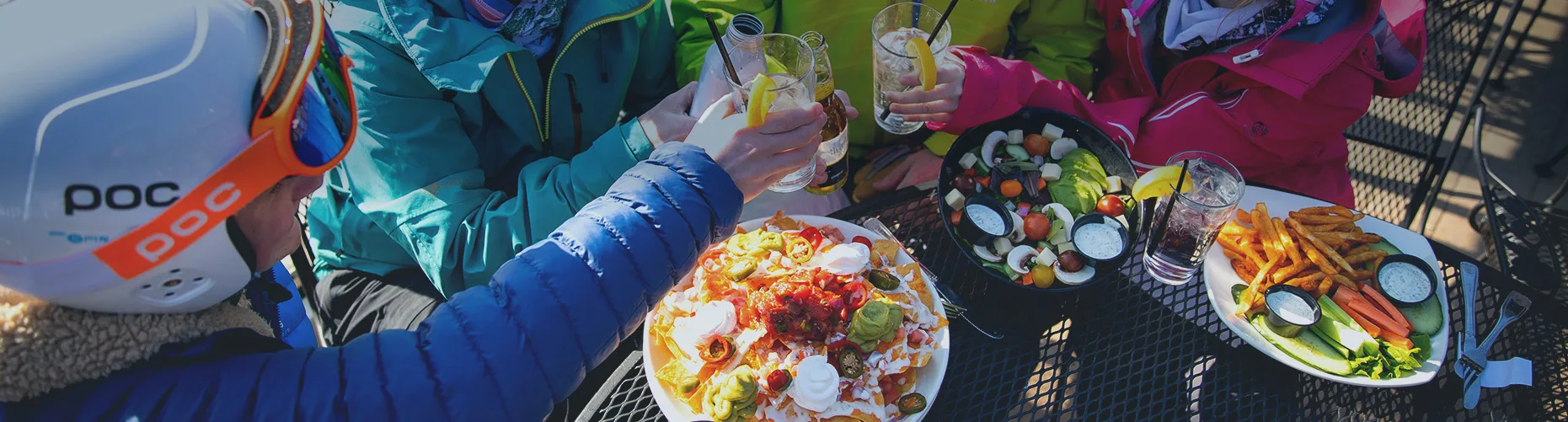 Skiers and riders eating at a table full of food